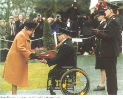 Queen Elizabeth II presented the George Cross to Constable Paul Slaine, who accepted it on behalf of the RUC. Paul was a police officer who lost both legs in an IRA mortar bomb attack in 1992.