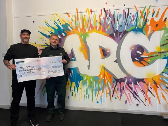Gary Rutherford, founder of ARC and NPT Sergeant Johnston with a cheque for £705 that officers raised by completing a charity coastal walk