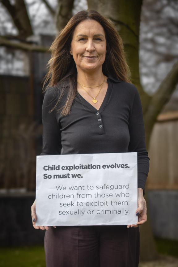 Detective Chief Inspector Claire Gilbert holding a sign saying, Child exploitation evolves. So must we. We want to safeguard children from those who seek to exploit them, sexually or criminally.